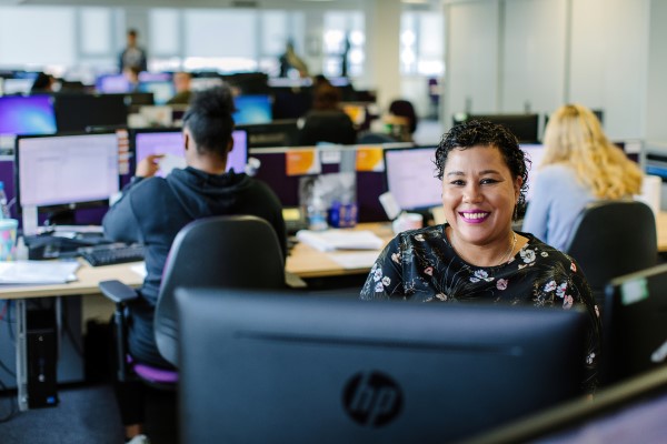 Female debt advisor sat at computer smiling.